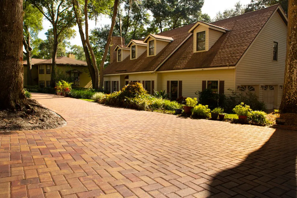 Entrada de autos y patio de pavers rojos tipo ladrillo frente a una casa de dos pisos con buhardillas